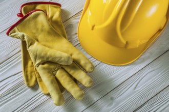 Yellow leather work gloves and construction helmet on old white lacquered wooden panels