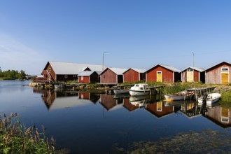 Svedjehamm, Finland - 28 July, 2021: colorful fishing cottages and boats reflected in the water