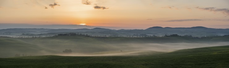 Sunrise with foggy atmosphere in hilly landscape, province of Siena, Tuscany, Italy