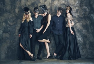 Group of people in masquerade carnival mask posing in studio. Beautiful women and men wearing