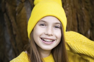 Cute and happy teenage girl with braces smiling at camera in yellow clothes in park. Concept of