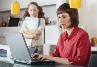 Mother and teenager girl with laptop computer together at home, Belgium