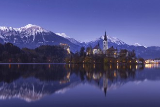 Scenic view of lake Bled at winter night with castle rock and St Martin church under beautiful