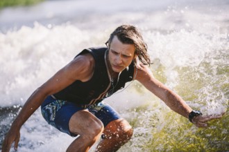Active wakesurfer jumping on wake board down the river waves. Surfer on wave. Male athlete training