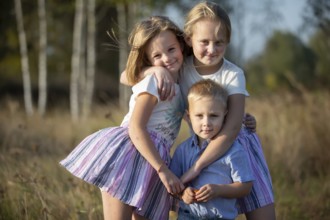 Little brother and two sisters are looking at the camera