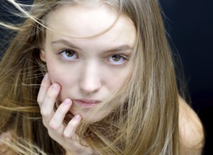 Portrait of the beautiful blonde woman with flying long hair. She is in the studio