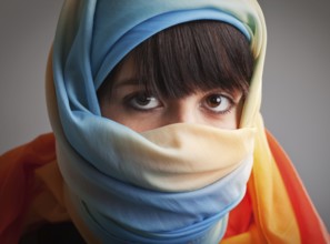 Brunette girl in multicolored head scarf, photographed on gray background, Unna, Germany