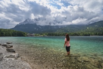 Zugspitze Peak top of Germany Alps mountain range and Eibsee Lake with woman tourist, Garmisch