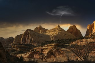 Large rocks in a desert landscape at dusk with a single flash in the sky, Monument Valley, Maxican