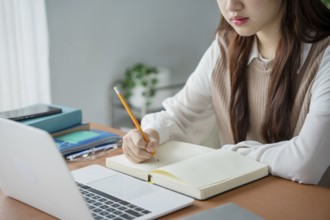 Asian woman using laptop to study student engaged in online learning at college