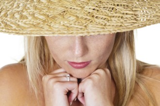 A young, thoughtful woman with a straw hat. portrait in front of a white background Austria