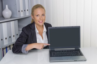 A young woman in her office with a laptop computer. Shows on the screen Austria