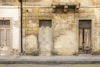 Marsakala, Malta, 01 07 2022: Yellow facade of a traditional worn house in nature stone