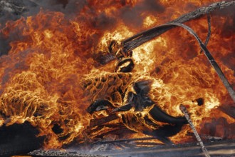 Burning cars wheels, strong flame of red-orange fire and clouds of black fumes. Selective focus,