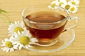 Herbal tea in a glass cup with saucer, camomile on a background of bamboo napkins