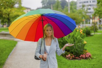 A young woman walks in the rain with a colourful umbrella in her hand. Austria