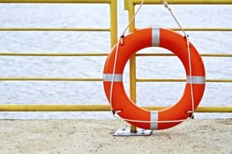 Lifebuoys red hanging on the yellow fence on the background of water