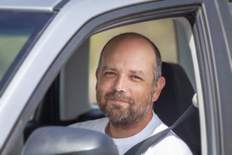 An image of a bearded man sitting in his car