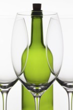 Three empty glasses of wine and green bottle on the white background
