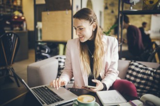 Business woman freelance working on computer notebook laptop and mobile phone, with coffee cup on