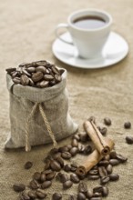 Cinnamon and cup of coffee on sacking