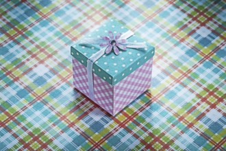 Wrapped gift box on checked fabric background celebrations concept
