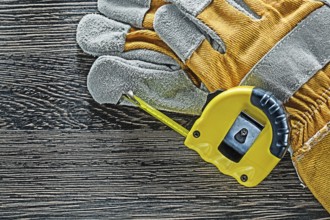 Tape measure pair of protective gloves on wooden board