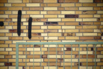 A wall made of old clinker bricks with an angular railing in front of it