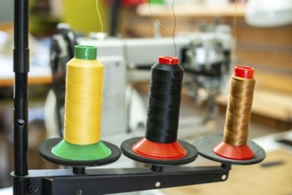 Threads and sewing machine in tailor shop. Close up