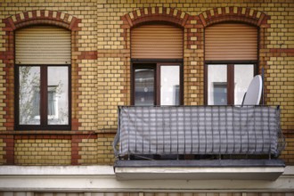 The façade of an old residential building with a clinker brick façade and a nostalgic balcony