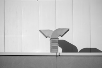 Extractor bonnets on the intermediate roof of a modern building cast shadows