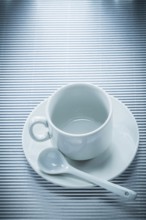 White ceramic cup saucer teaspoon on striped background