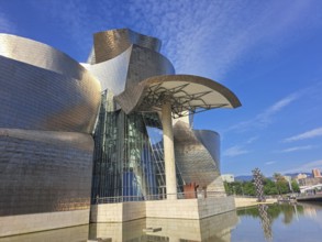 Futuristic building with curved metal shapes under a blue sky reflects innovative architecture,