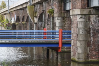 Brick bridge with blue-orange railings along a canal, Amsterdam, Netherlands