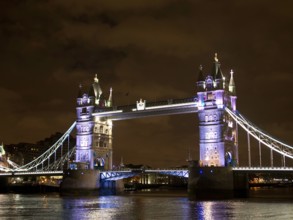 Bright lights of a historic bridge reflected in the calm river water, London, United Kingdom