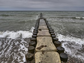 A long jetty leads into the sea, surrounded by waves and a cloudy sky, ahrenshoop, zingst, Baltic