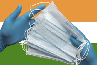 Doctor holding face masks in hands medical blue gloves on background national flag of India.