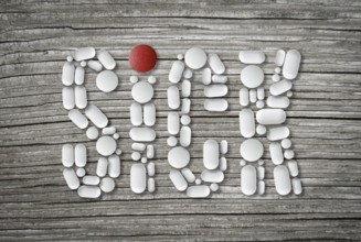 Conceptual Health Image Of Pills On A Wooden Table Spelling The Word Sick
