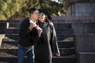 Transgender woman recent graduated, dressed in cap and gown, showing off his degree celebrating