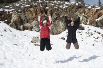 Two young happy teenage girls jumping with pleasure at snow. Troodos mountains Cyprus