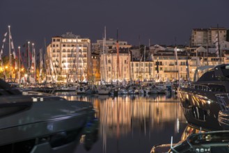 Yachts in the cannes bay at night. Illuminated buildings