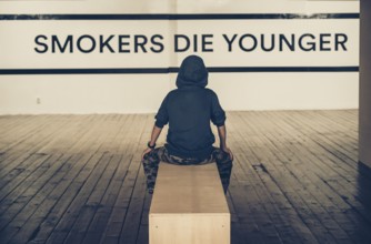 Teenager smoking and message on wall - Smokers die younger. No smoking concept with child. Casual