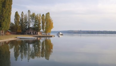 Scenic view with a house on the riverbank of Nistru river and a yacht floating. Autumn season