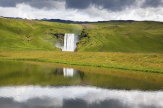 An incredible reflection. Abounding waterfall Skogafoss reflected in a small pond near the road