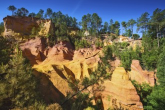 Unique red and orange hills in the province of Languedoc - Roussillon, France. Green trees create a