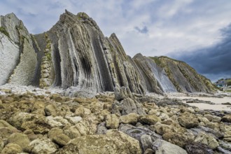Portio Beach, Cantabria Beaches. Giant rough gray rocks and smooth sandy beach. Noon on the beach