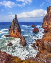 The sharp red rocks, boiling turquoise surf. The blinding midday sun illuminates the rocky shore.