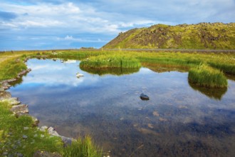 Small lake with thermal water. In the smooth surface of the water reflects the sky and clouds