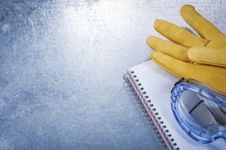 Safety glasses gloves copybook on metallic background
