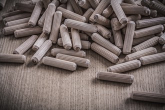 Variety of cylinder wooden dowels on wood board construction concept